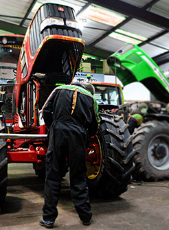 Persona revisando el motor de un tractor agrícola