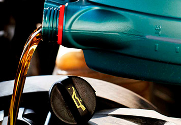 Botella de aceite semisintético vertiéndose en el motor del automóvil